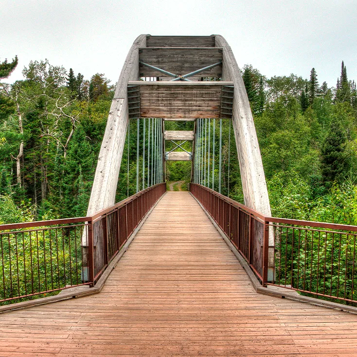 Grand pont suspendu en bois au-dessus d'une gorge.